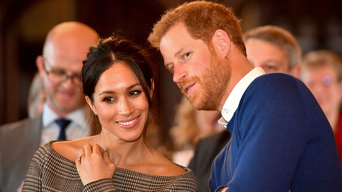 Britain's Prince Harry whispers to Meghan Markle as they watch a dance performance by Jukebox Collective in the banqueting hall during a visit to Cardiff Castle in Cardiff, Britain, January 18, 2018. REUTERS/Ben Birchall/Pool - RC1650CE75F0