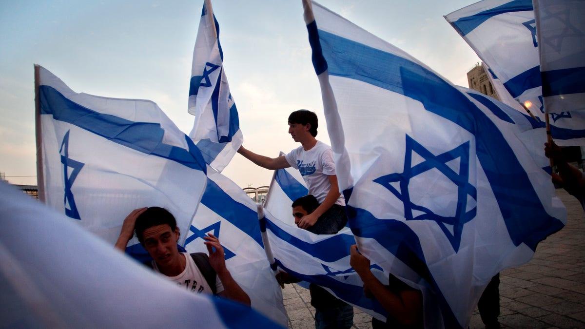 FILE - In this Monday, May 9, 2011 file photo, Israeli youths dance with Israeli flags, prior to a prayer at the Western Wall, the holiest site where Jews can pray, marking Israel's Independence Day,in Jerusalem. The notion of Israel’s “Jewishness” has gained both currency and controversy recently because of Prime Minister Benjamin Netanyahu’s demand that the Palestinians recognize it explicitly as part of an agreement and plans by a broad-based group of Israelis to lobby the Knesset to declare the country a Jewish state by law. (AP Photo/Sebastian Scheiner, File)