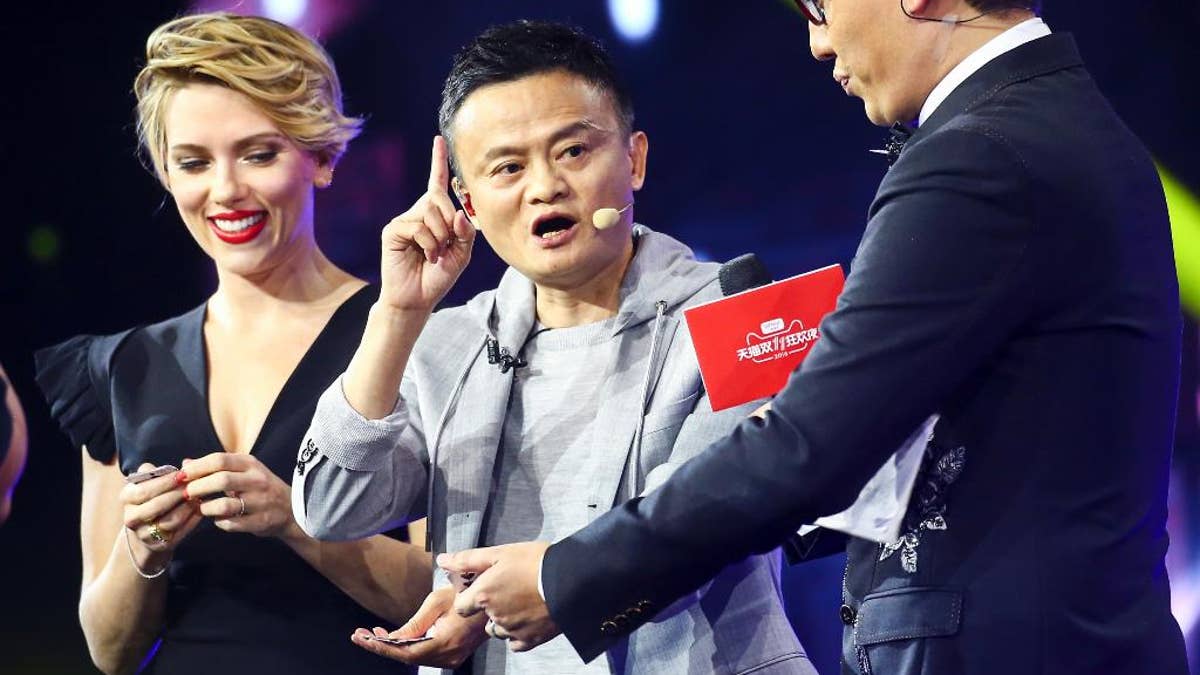 In this Thursday, Nov. 10, 2016 photo, Hollywood actress Scarlett Johansson, left, and Alibaba Group Chairman Jack Ma, center, attend an evening gala on the eve of the Singles Day online shopping festival in Shenzhen in southern China's Guangdong province. China's online shoppers are engaging in a rare bright spot for its cooling economy — a quirky holiday dubbed 