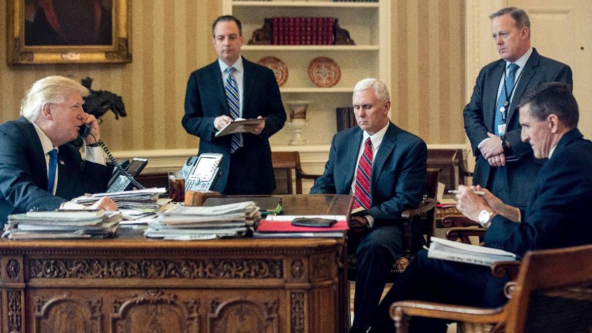 FILE - In this Jan. 28, 2017 file photo, President Donald Trump accompanied by, from second from left, Chief of Staff Reince Priebus, Vice President Mike Pence, White House press secretary Sean Spicer and then-National Security Adviser Michael Flynn speaks on the phone with Russian President Vladimir Putin, in the Oval Office at the White House in Washington. Trump's White House is nearly paralyzed by crisis, divisions and dysfunction. Virtually all policy announcements have slowed to a crawl. Aides are undercutting each other in leaks (AP Photo/Andrew Harnik, File)