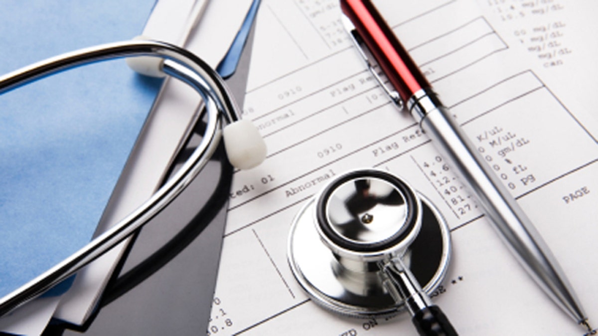 Stethoscope and pen resting on a sheet of medical lab test results, with patient file and x-ray or mri film