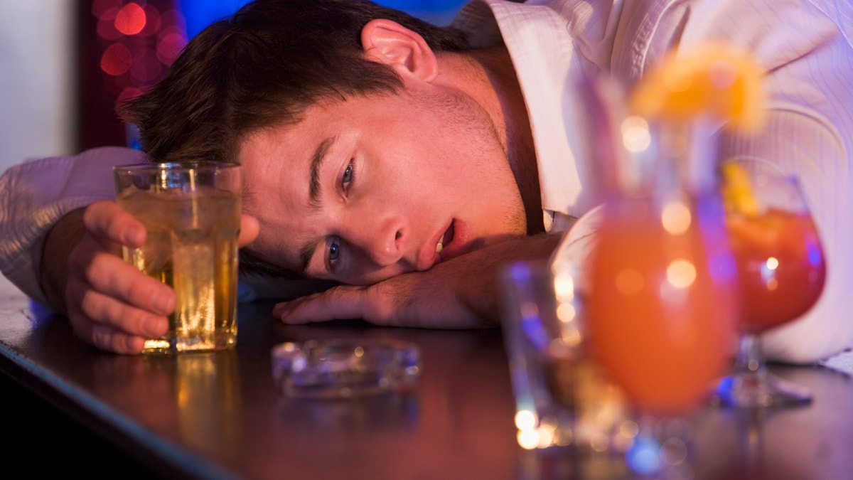 Drunk young man resting head on bar counter