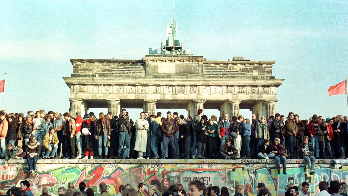 FILE PHOTO 10NOV89 - West Berlin citizens continue their vigil atop the Berlin Wall in front of the Brandeburg Gate in this November 10, 1989 file photo. The 10th anniversary off the "fall" of the Berlin wall is coming up on November 9, 1999. - RTXJABF