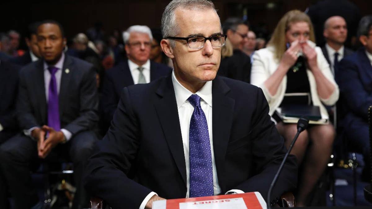 Acting FBI Director Andrew McCabe sits with a folder marked 