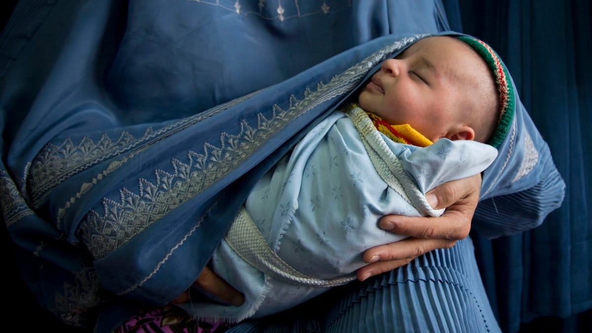In this Thursday, April 11, 2013 photo, an Afghan woman holds her newly born baby wrapped in her burqa  as she waits to get in line to try on a new burqa in a shop in the old town of Kabul, Afghanistan. Despite advances in womens rights, Afghanistan remains a deeply conservative country and most women continue to wear the Burqa. But tradesmen say times are changing in Kabul at least, with demand for burqas declining as young women going to school and taking office jobs refuse to wear the cumbersome garments. (AP Photo/Anja Niedringhaus)