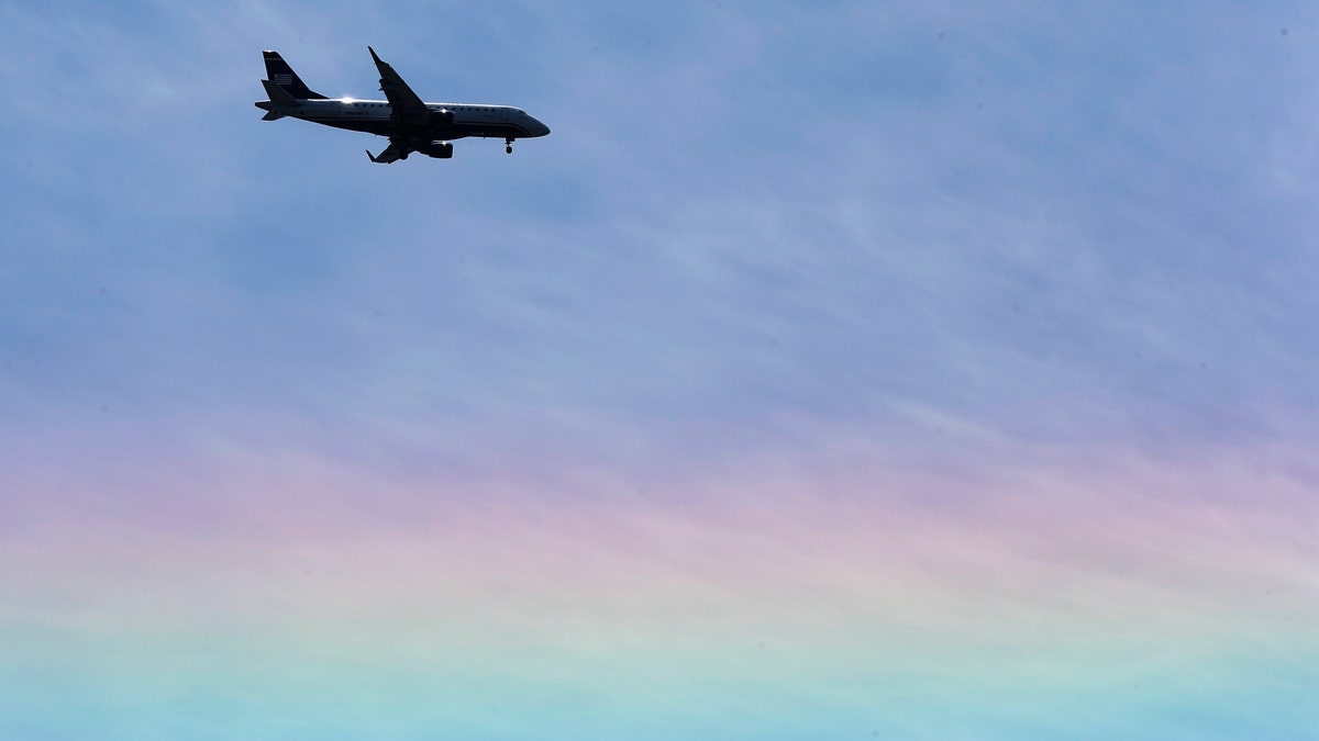An US Airways jet flies over a rainbow as descends to land Tuesday, May 14, 2013, in Philadelphia. (AP Photo/Matt Rourke)