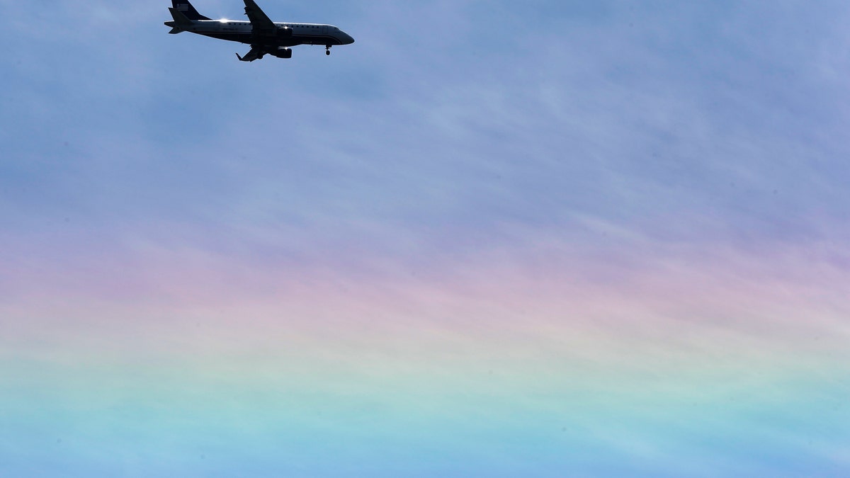 An US Airways jet flies over a rainbow as descends to land Tuesday, May 14, 2013, in Philadelphia. (AP Photo/Matt Rourke)