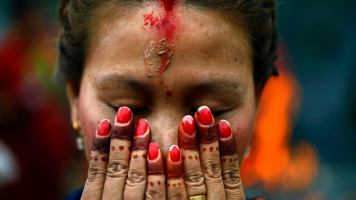 A Nepalese Hindu woman offers prayers at the Pashupatinath temple during Teej festival celebrations in Katmandu, Nepal, Tuesday, Sept. 18, 2012. During the festival, Nepalese Hindu women observe a day-long fast and pray for their husbands and for a happy married life. Those who are unmarried pray for a good husband. (AP Photo/Niranjan Shrestha)