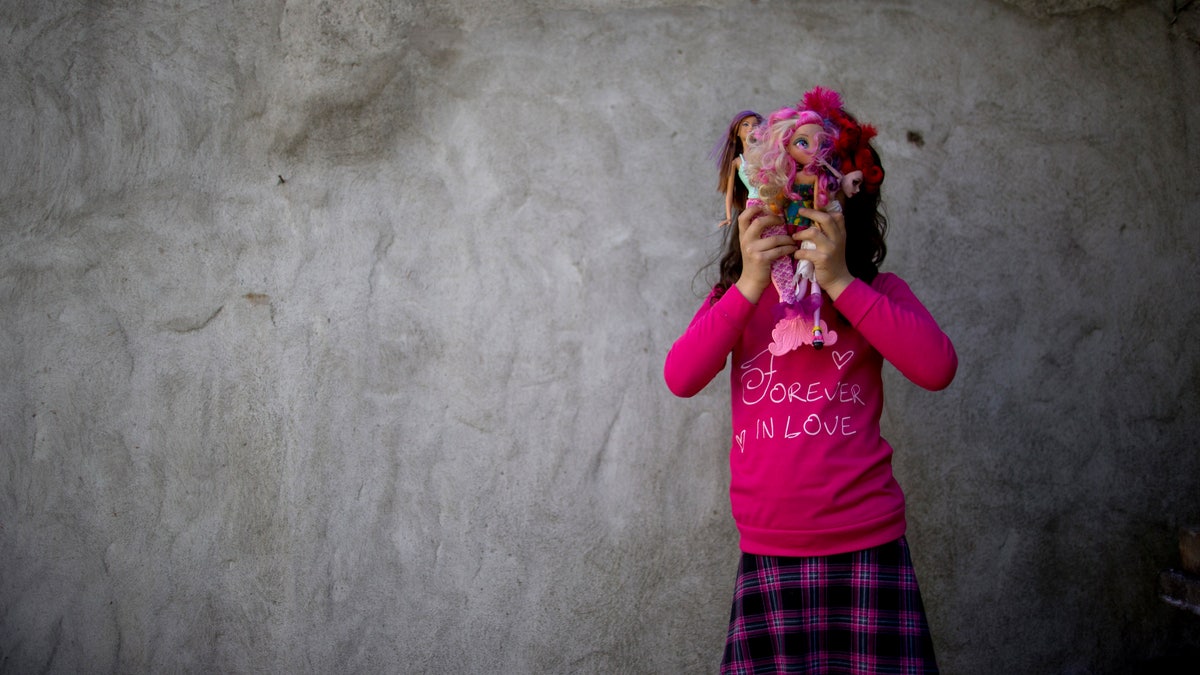 In this Sept. 29, 2015 photo, Luana poses for a portrait with her dolls at her home in Merlo, Argentina. When Luana and her identical twin brother were 3, a team of psychologists and doctors prescribed a regimen of "male reinforcement" for the child whose birth name is Manuel. He would only be allowed to play with male toys like action figures and wear boys' clothes. The color pink was prohibited, as were cartoons with female protagonists. When he was five, Manuel started calling himself Luana, and went on to become the youngest person to take advantage of a progressive Argentine law that allows people to identify their own gender for legal purposes. (AP Photo/Natacha Pisarenko)