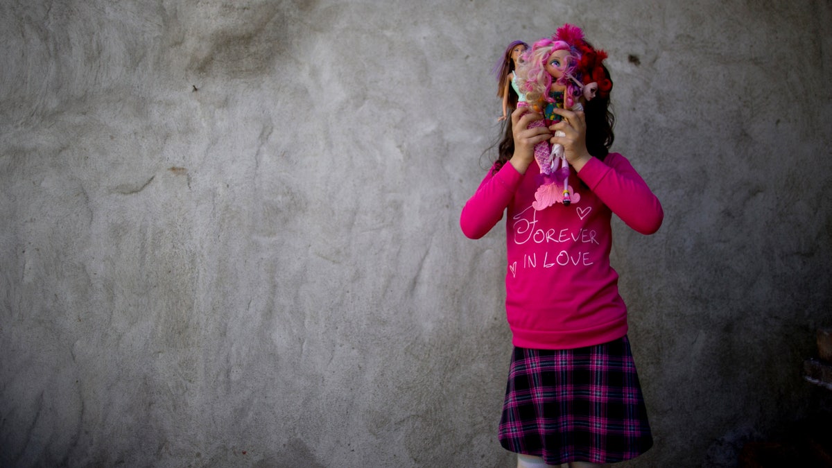 In this Sept. 29, 2015 photo, Luana poses for a portrait with her dolls at her home in Merlo, Argentina. When Luana and her identical twin brother were 3, a team of psychologists and doctors prescribed a regimen of "male reinforcement" for the child whose birth name is Manuel. He would only be allowed to play with male toys like action figures and wear boys' clothes. The color pink was prohibited, as were cartoons with female protagonists. When he was five, Manuel started calling himself Luana, and went on to become the youngest person to take advantage of a progressive Argentine law that allows people to identify their own gender for legal purposes. (AP Photo/Natacha Pisarenko)