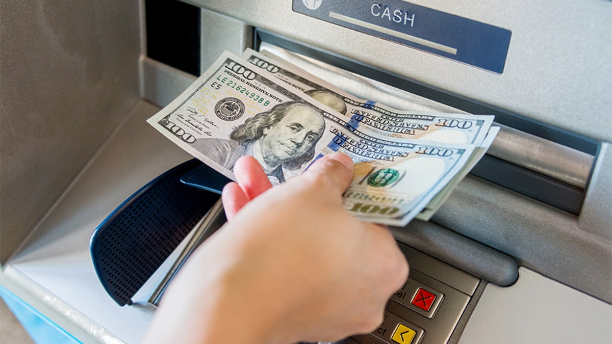 Woman hand taking money out of the ATM machine.