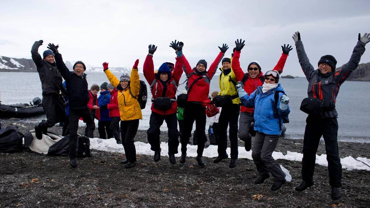 In this Feb. 2, 2015 photo, tourists jump as they pose for a picture, after disembarking from the Ocean Nova cruise ship, on King George Island, Antarctica. This tourist season, which runs November through March, more than 37,000 visitors are expected to walk on the coldest continent on Earth, about 10 percent more than the year before. (AP Photo/Natacha Pisarenko)