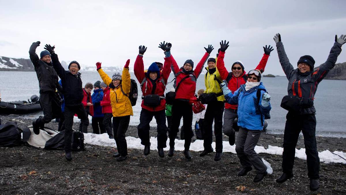 In this Feb. 2, 2015 photo, tourists jump as they pose for a picture, after disembarking from the Ocean Nova cruise ship, on King George Island, Antarctica. This tourist season, which runs November through March, more than 37,000 visitors are expected to walk on the coldest continent on Earth, about 10 percent more than the year before. (AP Photo/Natacha Pisarenko)