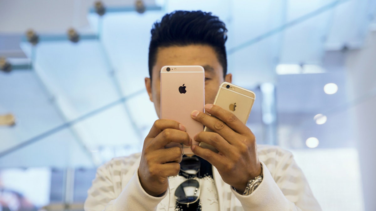 A man takes pictures as Apple iPhone 6s and 6s Plus go on sale at an Apple Store in Beijing, China Sept. 25, 2015. 