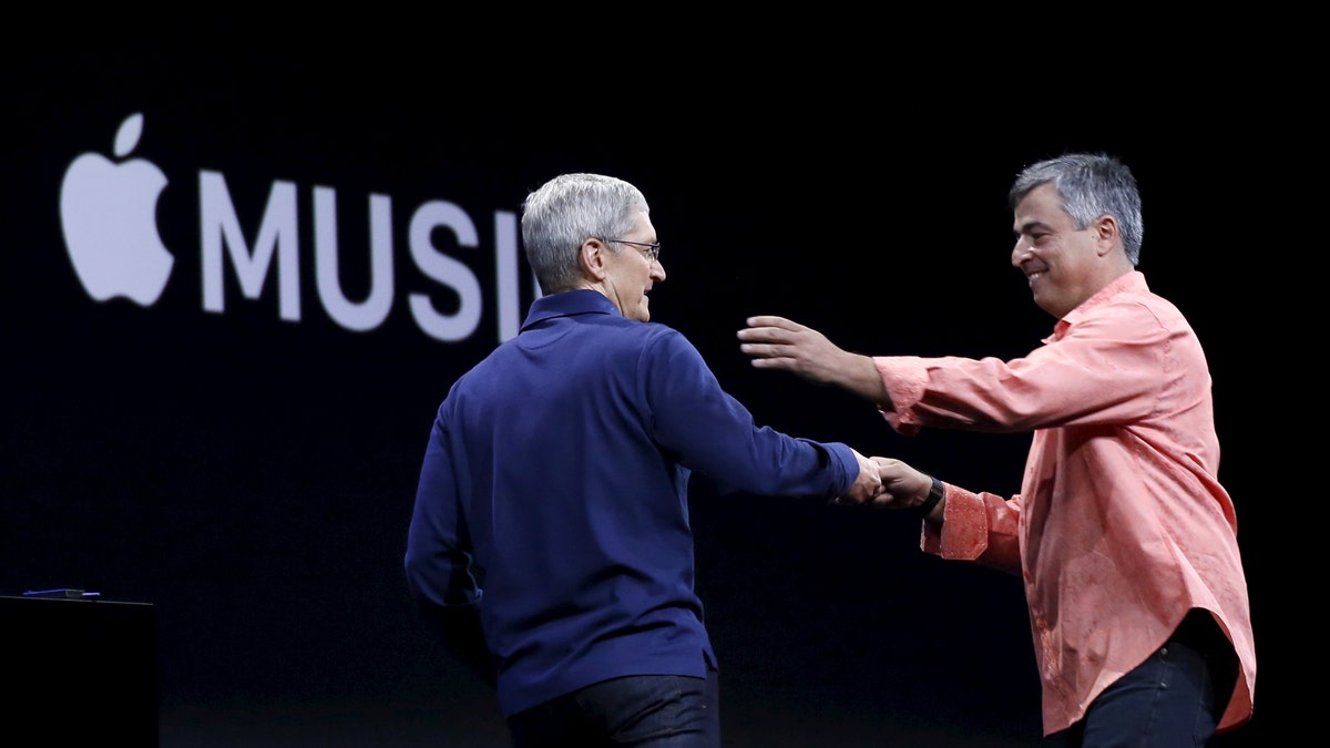 Apple CEO Tim Cook (L) greets senior vice president of internet services and software Eddy Cue during his keynote address at the Worldwide Developers Conference in San Francisco, California June 8, 2015.  