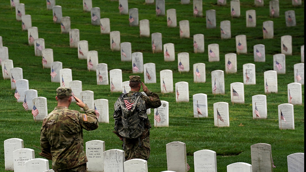 Soldiers from the 3rd U.S. Infantry Regiment (Old Guard) salute as Taps is heard nearby during "Flags-in", where a flag is placed at each of the 284,000 headstones at Arlington National Cemetery, ahead of Memorial Day, in Arlington, Virginia, U.S., May 25, 2017. REUTERS/Kevin Lamarque - RC1350BC2680