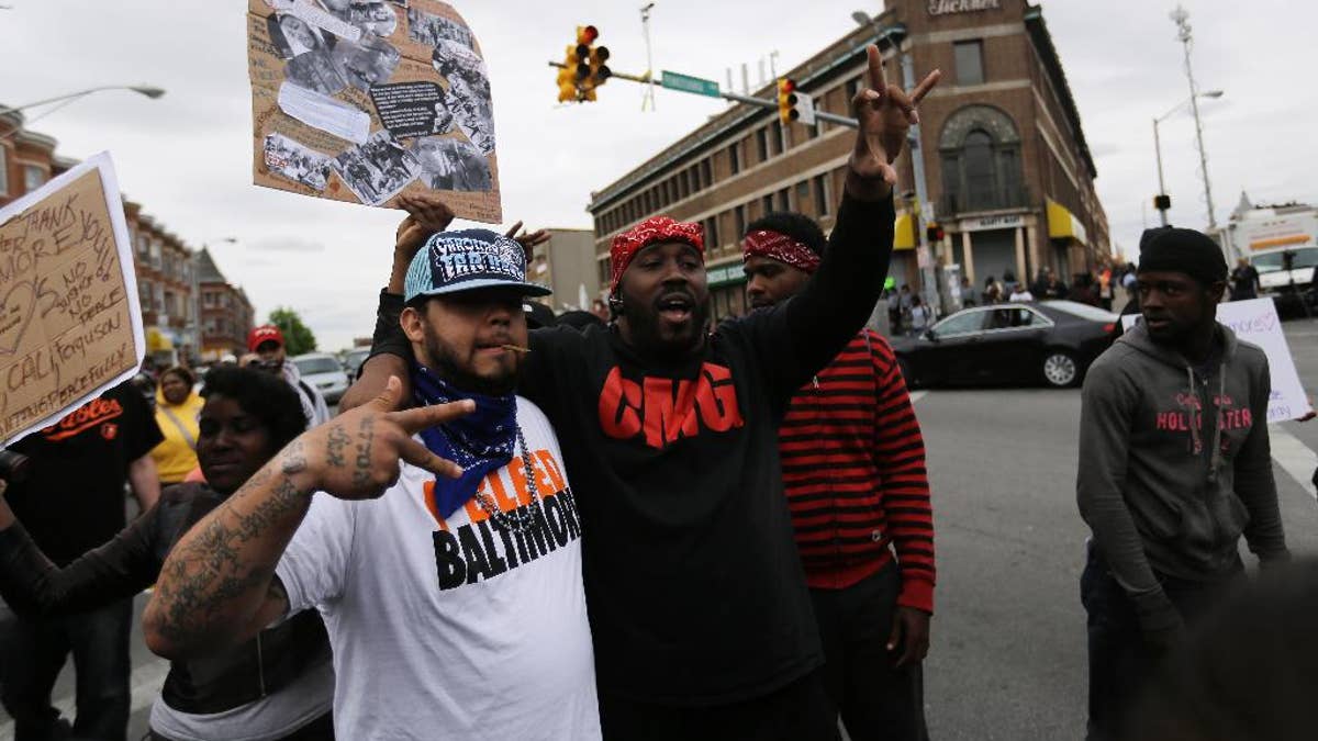 A man who calls himself Goldie Loc, left, walks with a man who calls himself Wolfe celebrating on Friday, May 1, 2015, after State's Attorney Marilyn J. Mosby announced criminal charges against all six officers suspended after Freddie Gray suffered a fatal spinal injury while in police custody in Baltimore. Loc said he is a member of the Crips gang and Wolfe said he was with the Bloods gang. (AP Photo/David Goldman)
