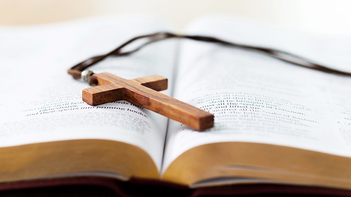 Bible and cross on desk.