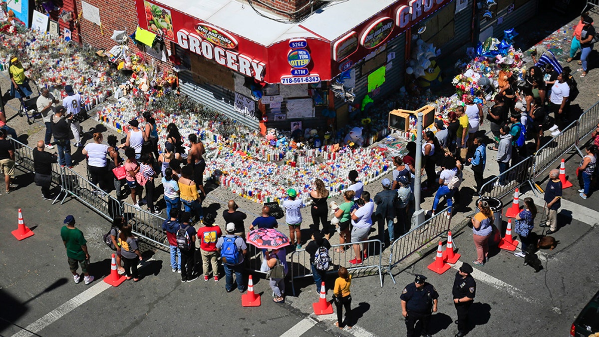 Mouners gather at a community memorial outside a bodega in New York on Tuesday, June 26, 2018, where 15-year-old Lesandro Guzman-Feliz was killed in a machete attack on Wednesday. (AP Photo/Bebeto Matthews)