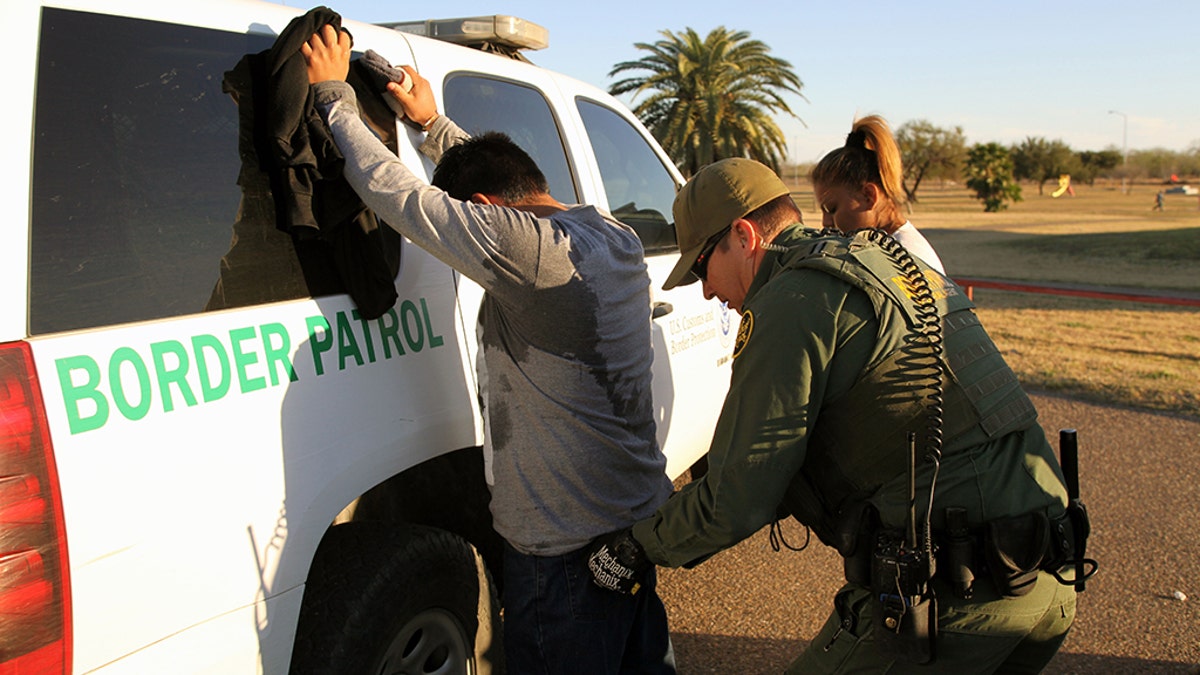 Rio Grande City, Texas, USA - February 9, 2016: A Border Patrol agent takes a Mexican man into custody for illegally entering the U.S. by crossing the Rio Grande River in the Rio Grande Valley in far south Texas. A continuous game of cat and mouse plays out along the river twenty four hours a day.