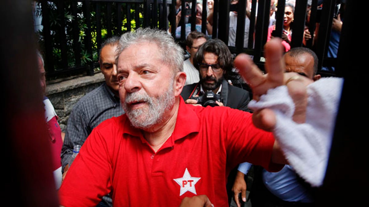 FILE - In this March 5, 2016 file photo, Brazil's former President Luiz Inacio Lula da Silva greets supporters who gathered outside his residence in Sao Bernardo do Campo, in the greater Sao Paulo area, Brazil. A Brazilian judge has ruled that Silva will stand trial on charges of money laundering and corruption. Judge Sergio Moro said Tuesday, Sept. 20, 2016 there is enough evidence to start a judicial process against Silva, his wife and six others in a widening corruption probe centered on the country's huge state-run oil company, Petrobras. (AP Photo/Andre Penner, File)
