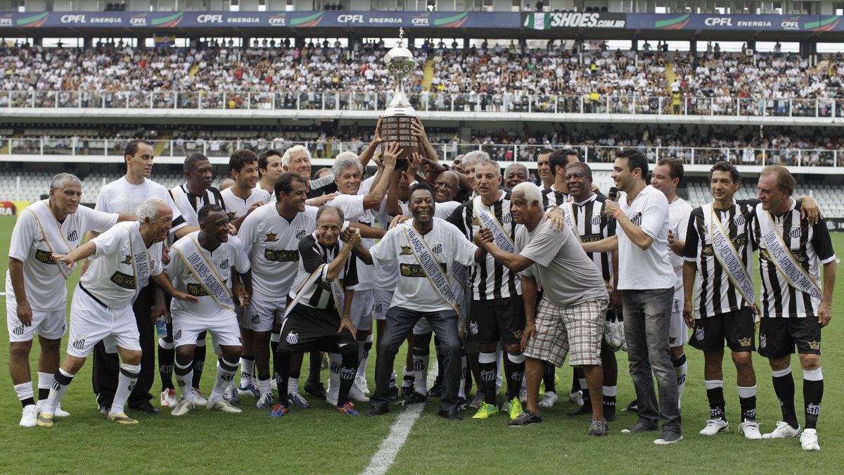 Pele, center, with other former Santos soccer players hold up the Libertadores championship trophy during during the centennial anniversary celebration of the team in Santos, Brazil, Saturday, April 14, 2012. Santos, the Brazilian club which ruled football with "The King" Pele in the 1960's, turns 100 with a rich history to show, including many major titles and remarkable victories that make the club one of the most successful in football. (AP Photo/Nelson Antoine)