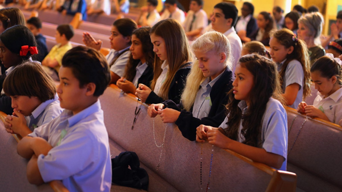 MIAMI, FL - DECEMBER 21: Children pray during a service, at St. Rose of Lima School, for the victims of the school shooting one week ago in Newtown, Connecticut on December 21, 2012 in Miami, Florida. Across the country people marked the one week point since the shooting at Sandy Hook Elementary School in Newtown, Connecticut that killed 26 people. (Photo by Joe Raedle/Getty Images)
