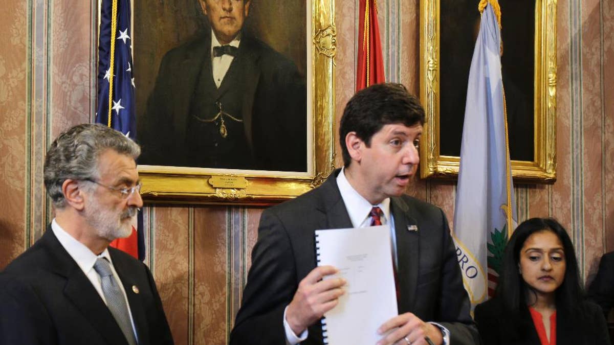 U.S. Attorney Steven Dettelbach, center, holds up the settlement agreement with the City of Cleveland as he speaks at a news conference Tuesday, May 26, 2015, in Cleveland. Cleveland agreed to overhaul its police department under the supervision of a federal monitor in a settlement announced Tuesday with the U.S. Department of Justice over a pattern of excessive force and other abuses by officers. The announcement comes three days after a white patrolman was acquitted of voluntary manslaughter charges in the shooting deaths of two unarmed black suspects in a 137-shot barrage of police gunfire following a high-speed chase. The case helped prompt an 18-month investigation by the Justice Department. Cleveland Mayor Frank Jackson, left, and Vanita Gupta, head of civil rights division at the Department of Justice, right, listen. (AP Photo/Tony Dejak)