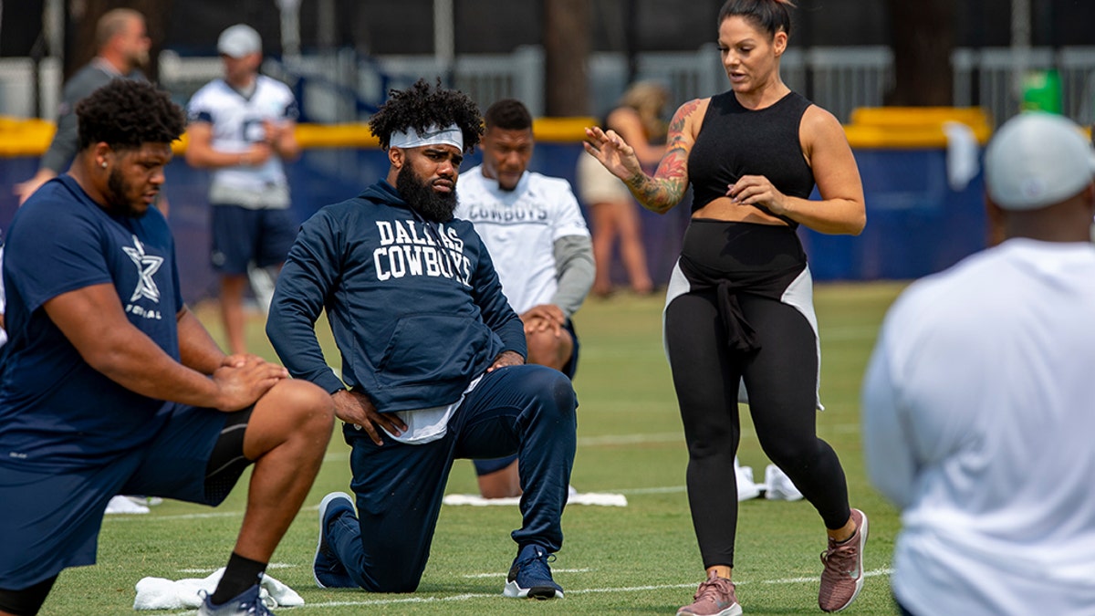 Dallas Cowboys offensive tackle La'el Collins, left and running back Ezekiel Elliott, center, listen to yoga instructor Stacey Hickman