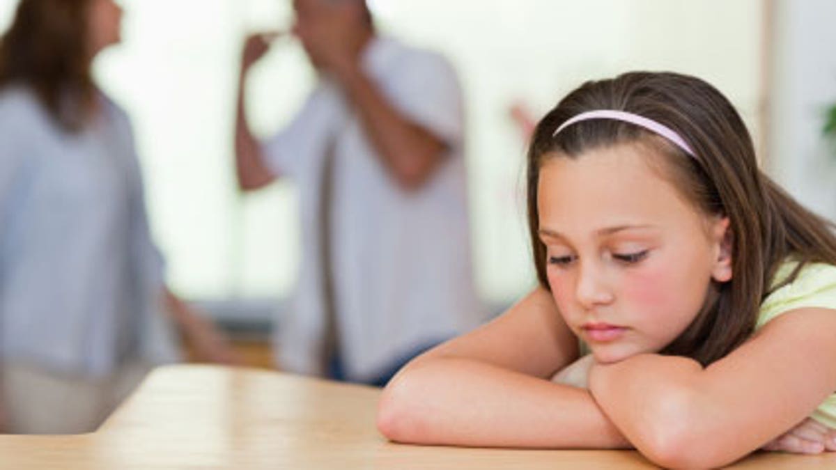 Sad girl with her fighting parents behind her