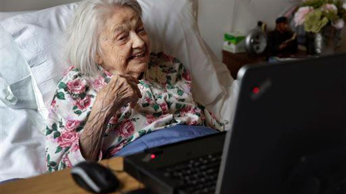 Patient Louise Irving watches a laptop computer with her daughter's morning wake-up video playing, at The Hebrew Home of Riverdale, in New York, Wednesday, March 25, 2015. The nursing home in the Bronx has started a pilot program in which relatives record video messages for patients of Alzheimer's and other forms of dementia. The videos are played for them each morning to calm their agitation and reassure them about their surroundings and their routines.