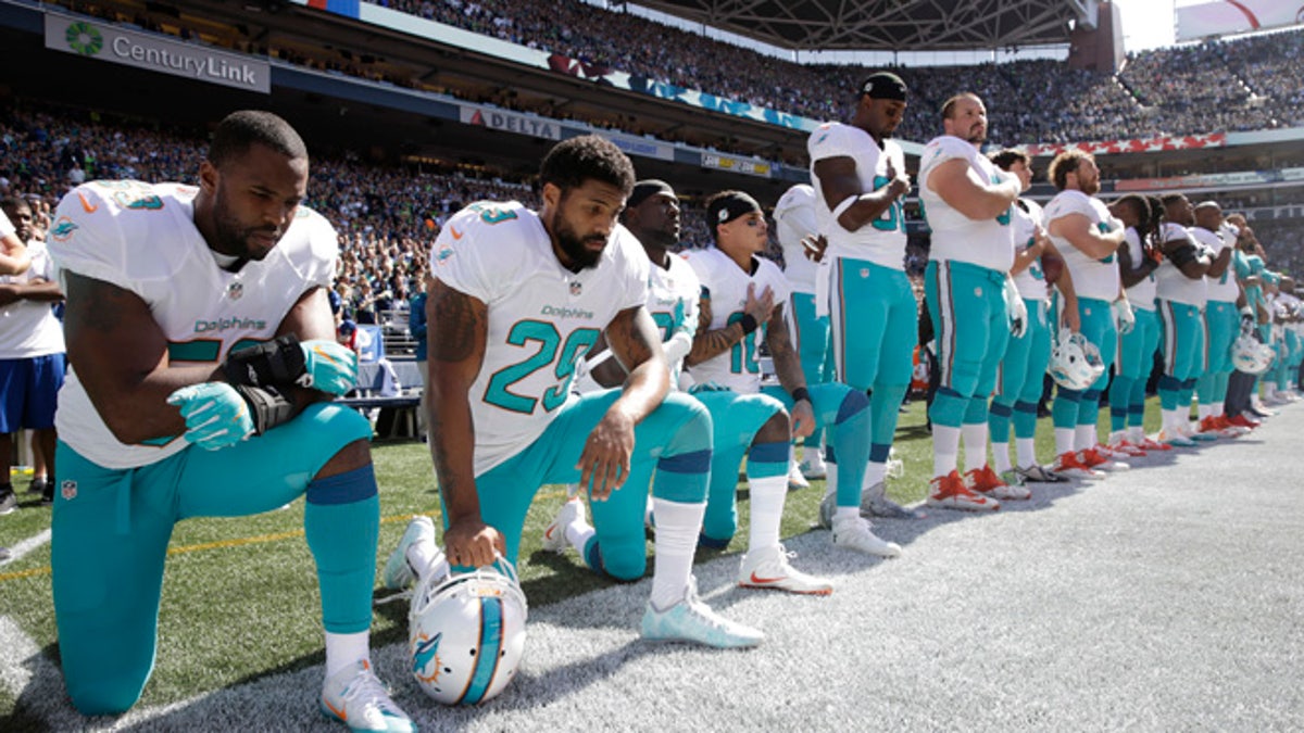 From left, Miami Dolphins' Jelani Jenkins, Arian Foster, Michael Thomas, and Kenny Stills, kneel during the singing of the national anthem before an NFL football game against the Seattle Seahawks, Sunday, Sept. 11, 2016, in Seattle. (AP Photo/Stephen Brashear)