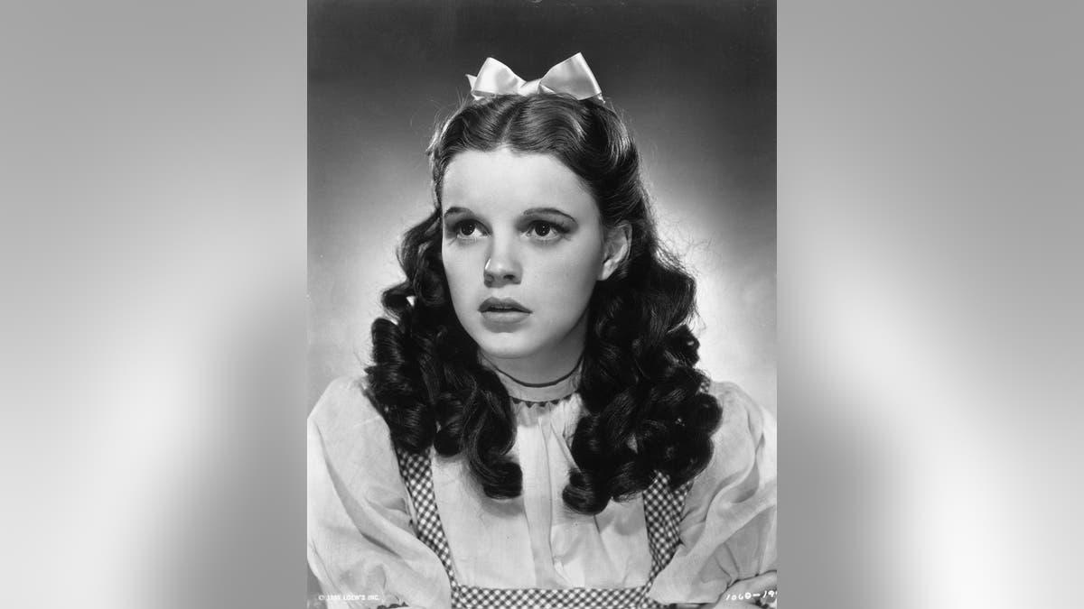 1939:  Promotional studio portrait of American actor and singer Judy Garland (1922 - 1969) wearing her costume as Dorothy from director Victor Fleming's film, 'The Wizard of Oz'.  She wears a gingham bodice and a white puff-sleeved blouse, with a satin ribbon in her hair.  (Photo by MGM Studios/MGM Studios/Getty Images)