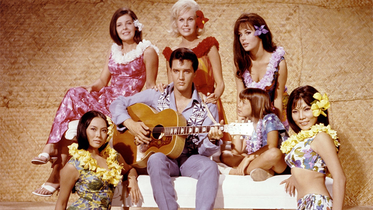 American singer and actor Elvis Presley surrounded by Korean actress Linda Wong, American Julie Parrish, British Suzanna Leigh, American Marianna Hill, American Donna Butterworth (little girl), and Chinese Irene Tsu, on the set of Paradise, Hawaiian Style directed by Canadian Michael D. Moore. (Photo by Sunset Boulevard/Corbis via Getty Images)