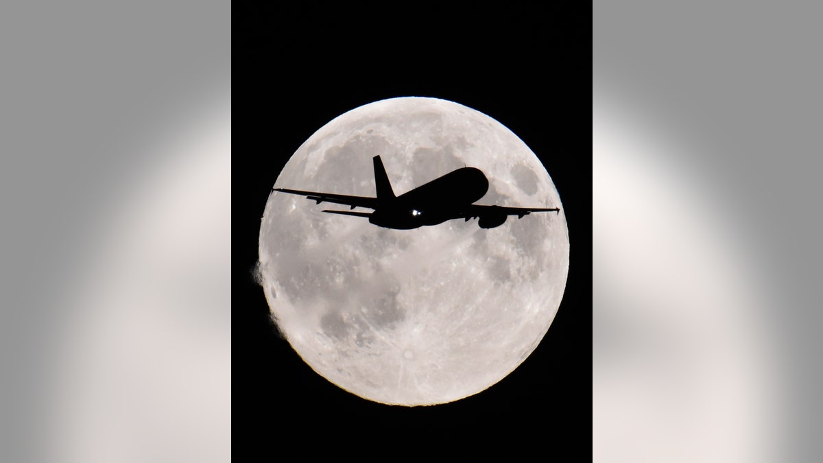 A passenger aircraft descends towards Heathrow Airport with a full moon seen behind, in west London, Sept. 8. The September full moon, also known as the Harvest Moon, is the last of this summer's three 