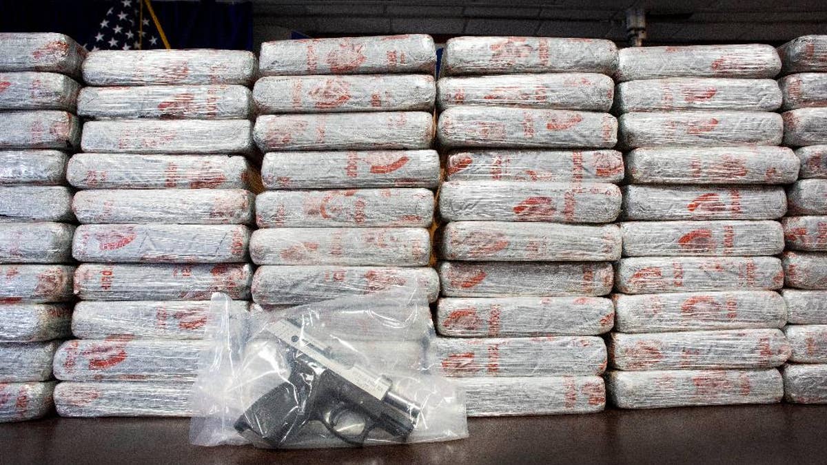 A firearm and 154 pounds of heroin worth at least $50 million are displayed at a Drug Enforcement Administration news conference, Tuesday, May 19, 2015 in New York. The DEA called the heroin seizure its largest ever in New York state. Officials said on Tuesday that most of the drugs were found in an SUV in the Bronx following a wiretap investigation. (AP Photo/Mark Lennihan)