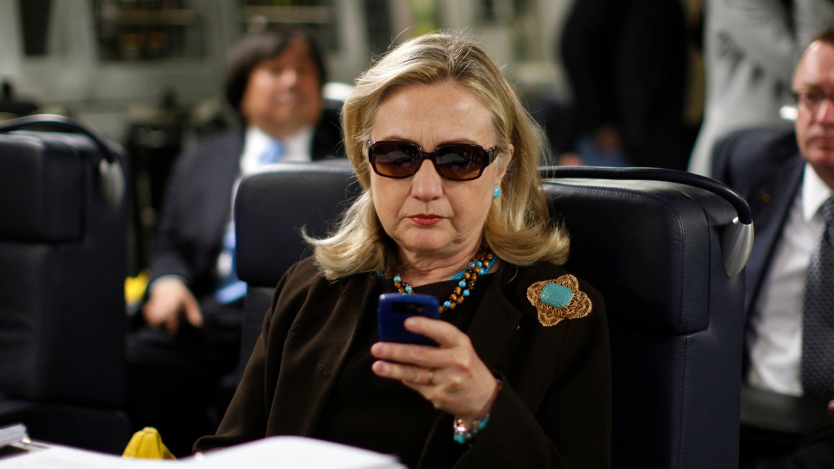 FILE - In this Oct. 18, 2011, file photo, then-Secretary of State Hillary Rodham Clinton works from a desk inside a C-17 military plane upon her departure from Malta, in the Mediterranean Sea, bound for Tripoli, Libya. Clinton has joined Twitter, describing herself as a "pantsuit aficionado" and a "hair icon." The potential 2016 presidential candidate's profile page shows the infamous photo of the stern-looking Clinton wearing dark sunglasses and reading her Blackberry. (AP Photo / Kevin Lamarque, Pool, File)