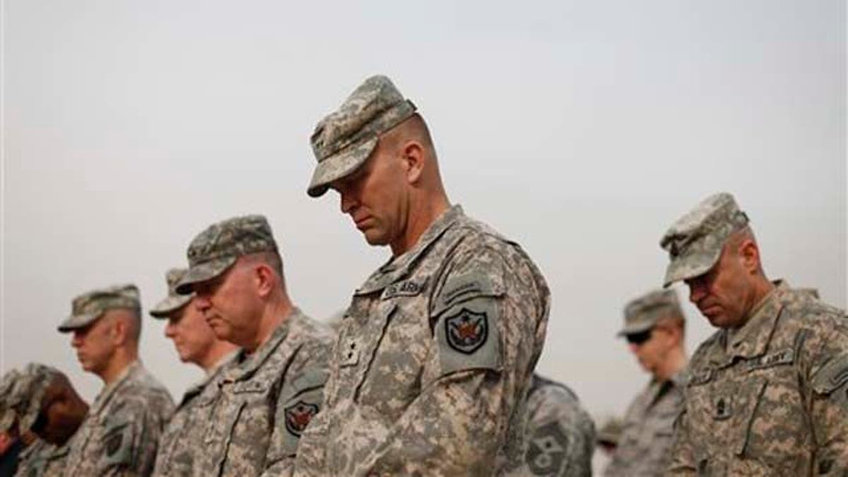 Military personnel lower their heads during ceremonies of the encasing of the US Forces Iraq colors, in Baghdad, Iraq, Thursday, Dec., 15, 2011. The ceremonies mark the official end of the US military mission in Iraq. (AP Photo/Pablo Martinez Monsivais, Pool)