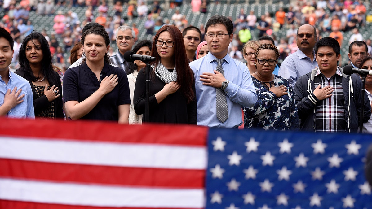 Thirty-two Ssoutheast Michigan immigrants recite the "Pledge of Allegiance" as they are sworn in to become United States citizens during a naturalization ceremony prior to a baseball game between the Detroit Tigers and the Kansas City Royals, Thursday, June 29, 2017, in Detroit. This is the 10th year the ceremony has taken place at Comerica Park during the baseball season. (AP Photo/Lon Horwedel)