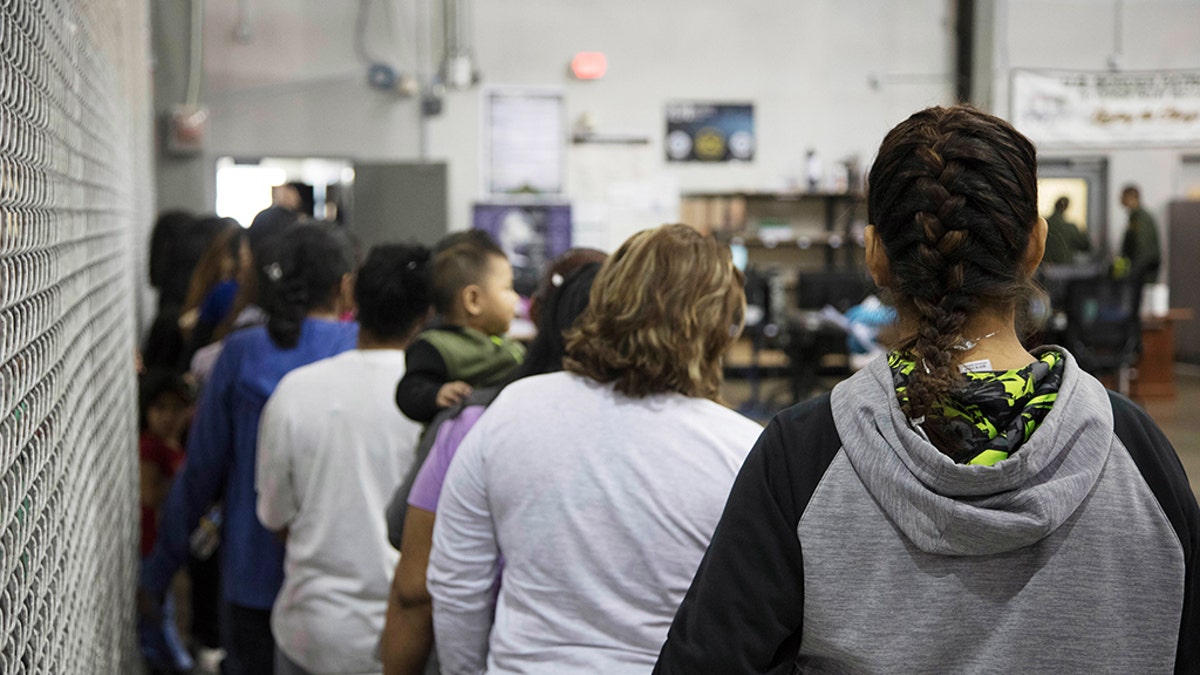 People who've been taken into custody related to cases of illegal entry into the United States, stand in line at a facility in McAllen, Texas, Sunday, June 17, 2018