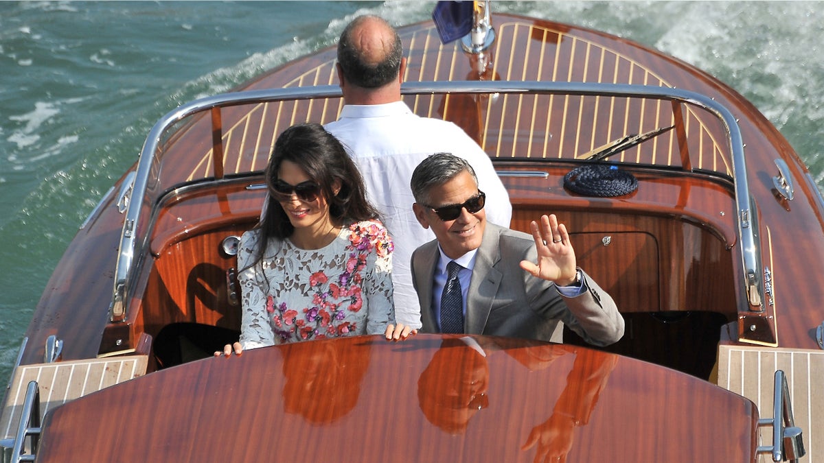 George Clooney and his wife Amal Alamuddin, cruise the Grand Canal after leaving the Aman luxury Hotel in Venice, Italy, Sunday, Sept. 28, 2014. George Clooney married human rights lawyer Amal Alamuddin Saturday, the actor's representative said, out of sight of pursuing paparazzi and adoring crowds. (AP Photo/Luigi Costantini)
