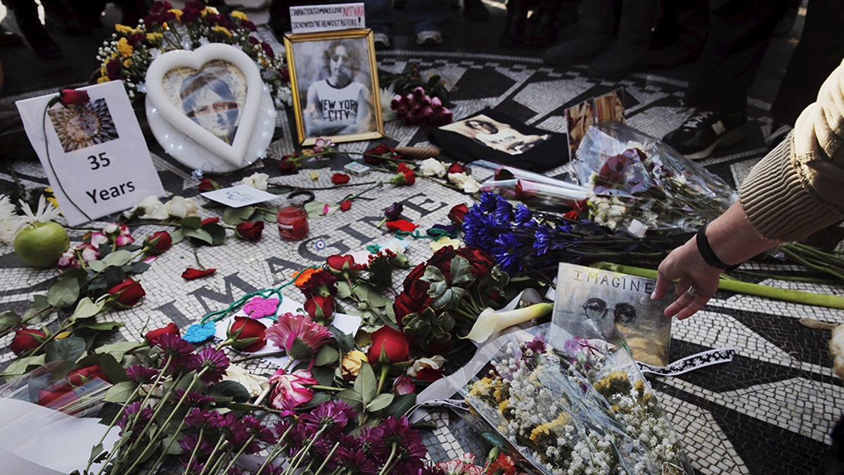 A woman sets a photograph down as she joins fans of former Beatle John Lennon who have gathered at the Imagine mosaic in the Strawberry Fields section of New York's Central Park