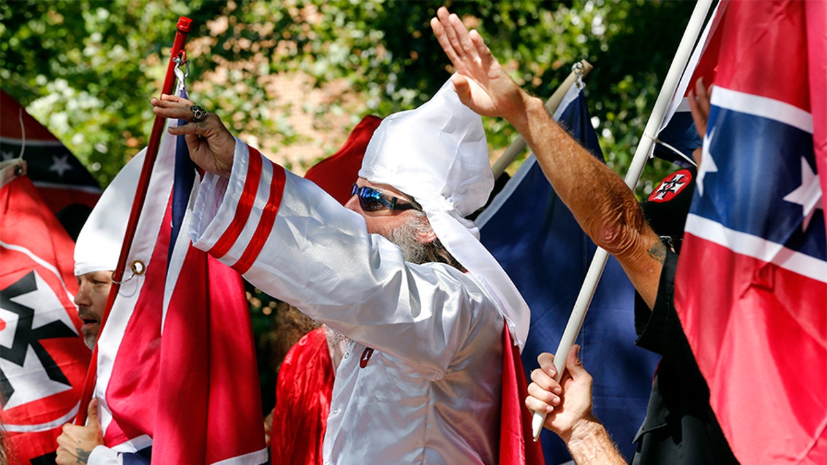 In this Saturday, July 8, 2017 photo, Klan members salute during a KKK rally in Justice Park, in Charlottesville, Va. The number of Ku Klux Klan chapters in the U.S. is plummeting as a new generation of khaki-clad racists rejects hoods and robes for a 