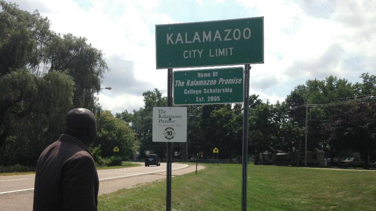 Kalamazoo Mayor Bobby Hopewell looks at a recently unveiled city limit sign honoring the Kalamazoo Promise, Friday, Aug. 14, 2015, in Kalamazoo, Mich. Announced in 2005, the anonymously funded program that pays the college tuition of students from the Kalamazoo public school district has given out $67 million in scholarships, and students have earned more than 850 degrees and post-secondary credentials. Close to 4,000 students have taken advantage. (AP Photo/ Mike Householder)