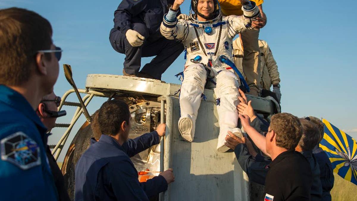 In this photo provided by NASA, United States astronaut Terry Virts is helped out of the Soyuz TMA-15M spacecraft just minutes after he and Russian cosmonaut Anton Shkaplerov, center, and Italian astronaut Samantha Cristoforetti landed in a remote area near the town of Zhezkazgan, Kazakhstan, Thursday, June 11, 2015. Virtz, Shkaplerov, and Cristoforetti are returning after more than six months onboard the International Space Station where they served as members of the Expedition 42 and 43 crews. (Bill Ingalls/NASA via AP)