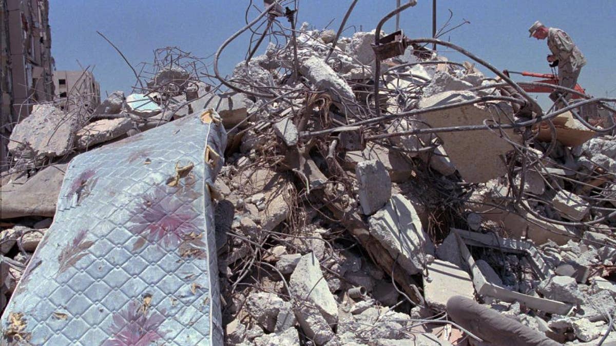 FILE - In this June 27, 1996 file photo, a U.S. Air Force officer climbs a pile of rubble to photograph the devastated building in Dhahran, Saudi Arabi where a truck bomb destroyed the eight story building behind Tuesday and killed 19 U.S. servicemen, injuring hundreds. A man suspected in the 1996 bombing of the Khobar Towers residence at a U.S. military base in Saudi Arabia has been captured, a U.S. official tells The Associated Press. Ahmed al-Mughassil , described by the FBI in 2001 as the head of the military wing of Saudi Hezbollah, is suspected of leading the attack that killed 19 U.S. service personnel and wounded almost 500 people.(AP Photo/Greg Marinovich, File)