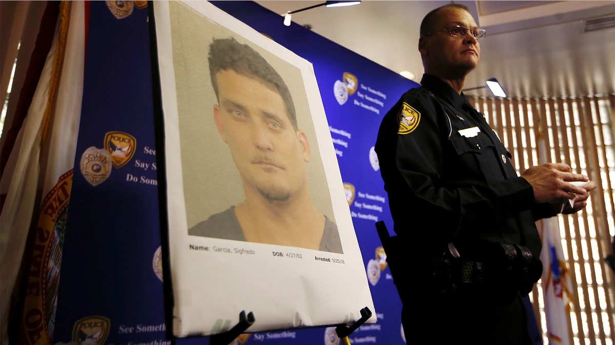 Tallahassee Police Department Public information officer David Northway reveals an image of Sigfredo Garcia, 34, during a press conference in Tallahassee, Fla., Thursday, May 26, 2016. Garcia is wanted for the murder of Florida State University law professor Dan Markel. Markel was killed in his Tallahassee home in July 2014. (Joe Rondone/Tallahassee Democrat via AP)