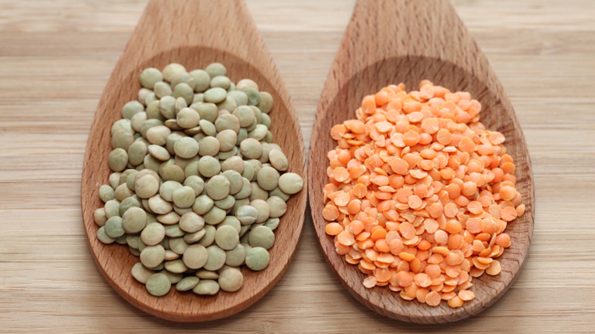 Green and red lentils in a wooden spoons