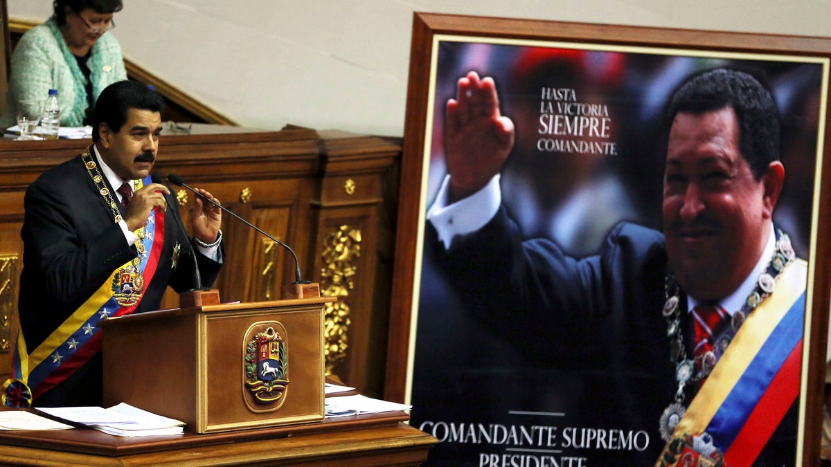 Venezuela's President Nicolas Maduro, left, speaks next to a framed poster featuring the late President Hugo Chavez during the annual state-of-the-nation address to the National Assembly in Caracas, Venezuela, Wednesday, Jan. 15, 2014. (AP Photo/Fernando Llano)