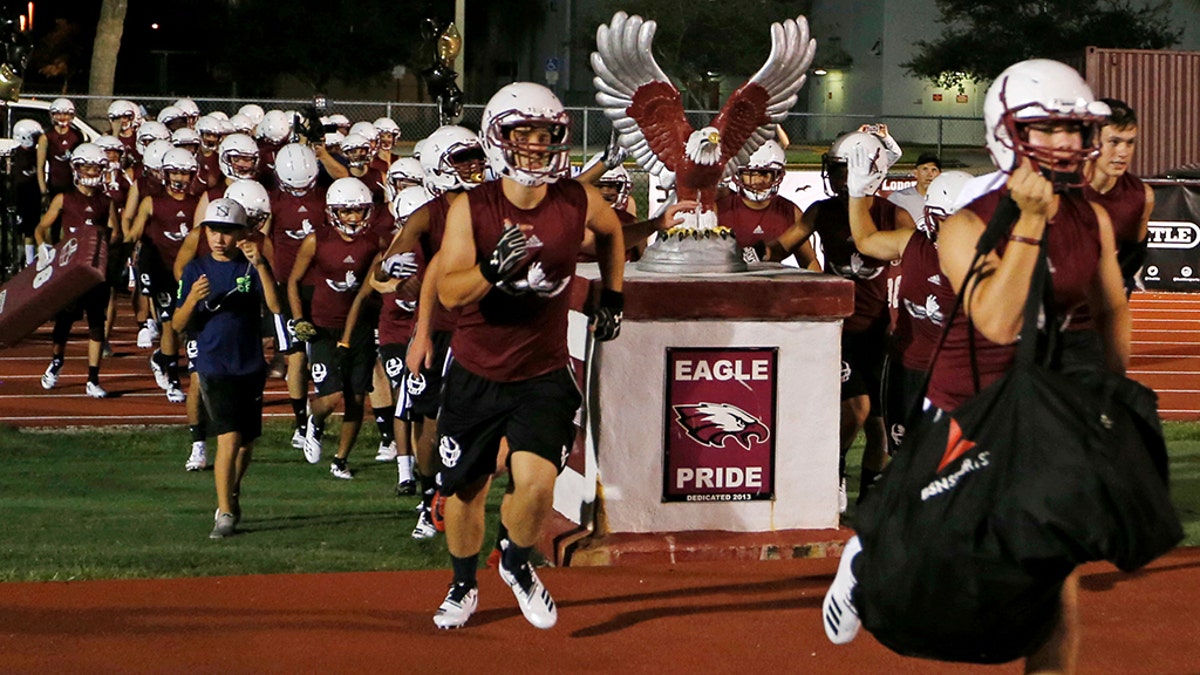 Members of the Marjory Stoneman Douglas High School football team take the field to begin practice for a new season just after midnight on Monday, July 30, 2018, in Parkland, Fla.